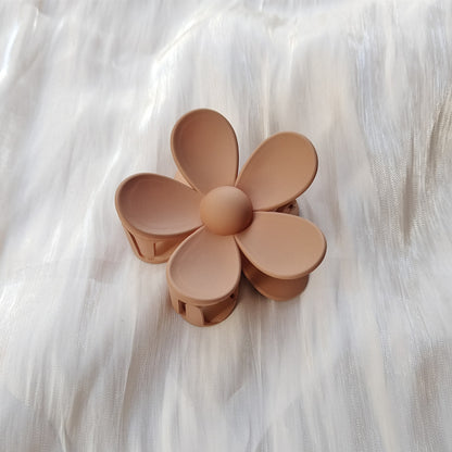 Colorful flower hair clip in matte pastel brown with five rounded petals on white fabric background