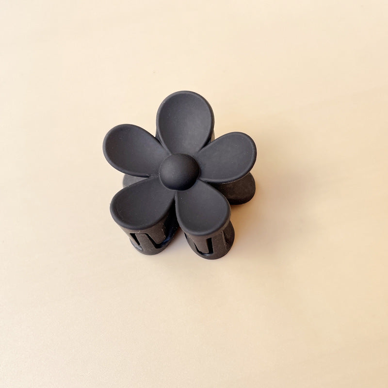 Black colorful flower hair clip with five frosted petals on beige background