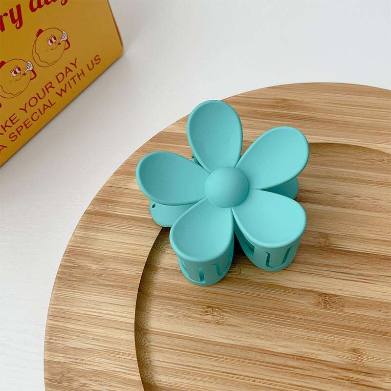Blue colorful flower hair clip shaped like a frosted five-petal flower on wooden surface