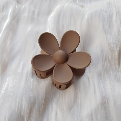 Matte brown colorful flower hair clip with five petals on white textured fabric background