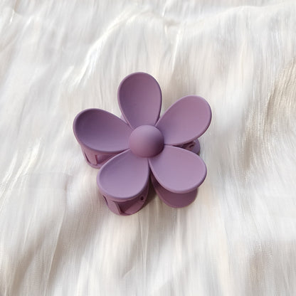 Purple colorful flower hair clip with frosted matte finish on white fabric background