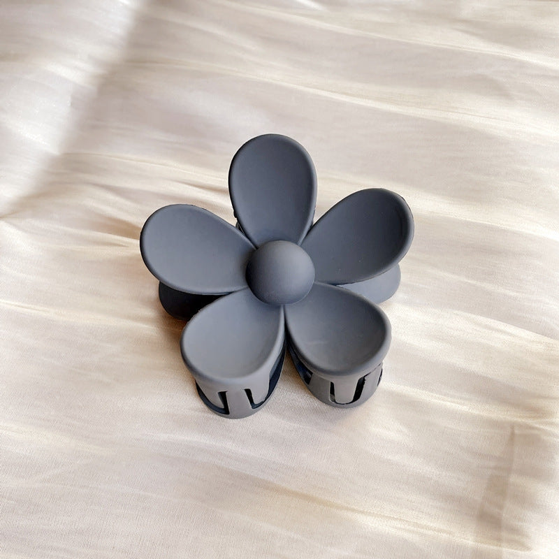 Matte gray colorful flower hair clip with five petals on a light fabric background