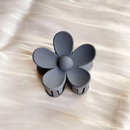 Matte gray colorful flower hair clip with five petals on a light fabric background