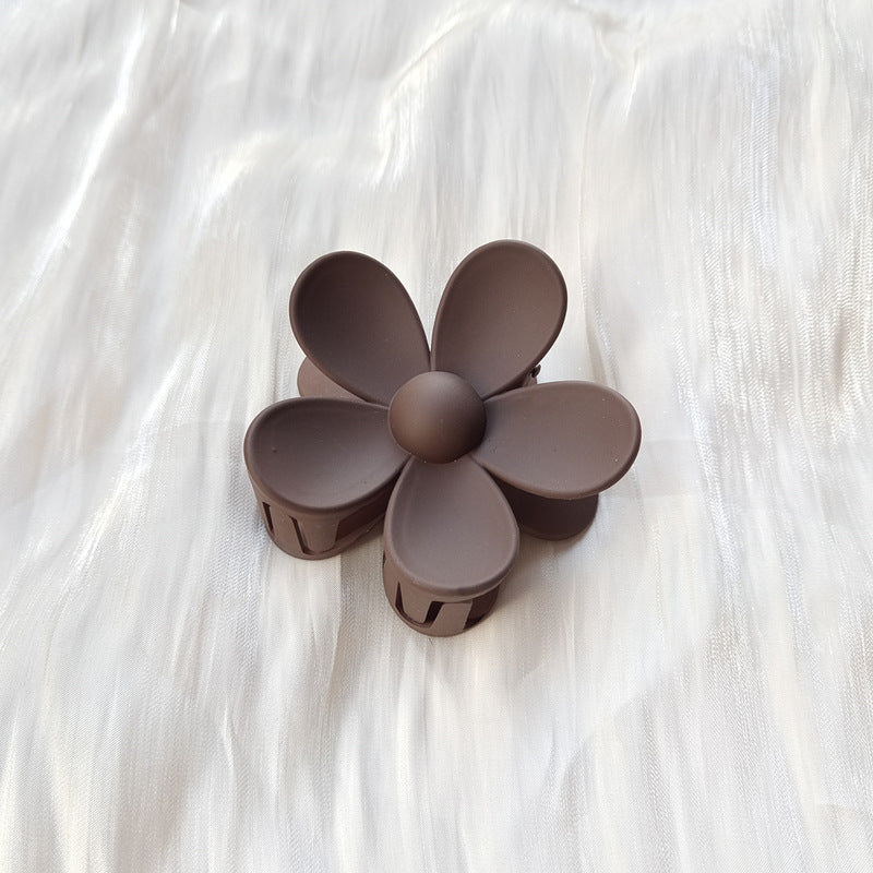 Brown colorful flower hair clip with frosted petals on white fabric background