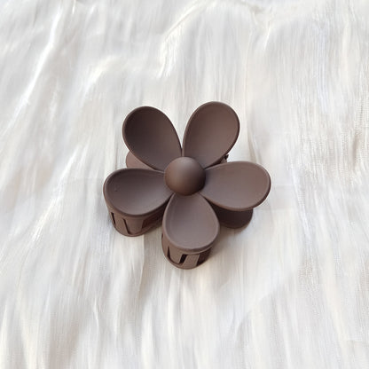 Brown colorful flower hair clip with frosted petals on white fabric background