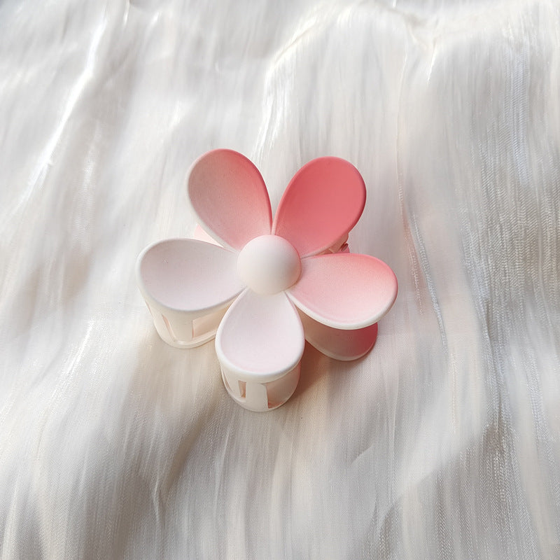 Colorful flower hair clip in pink and white frosted candy colors placed on white fabric