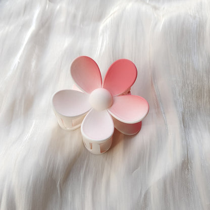 Colorful flower hair clip in pink and white frosted candy colors placed on white fabric