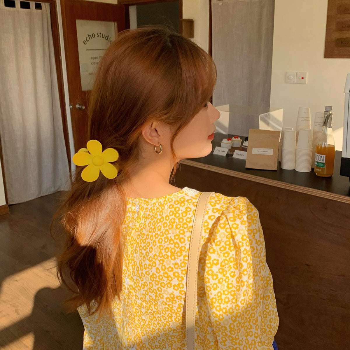 Woman wearing a yellow colorful flower hair clip in her brown hair with a yellow floral dress