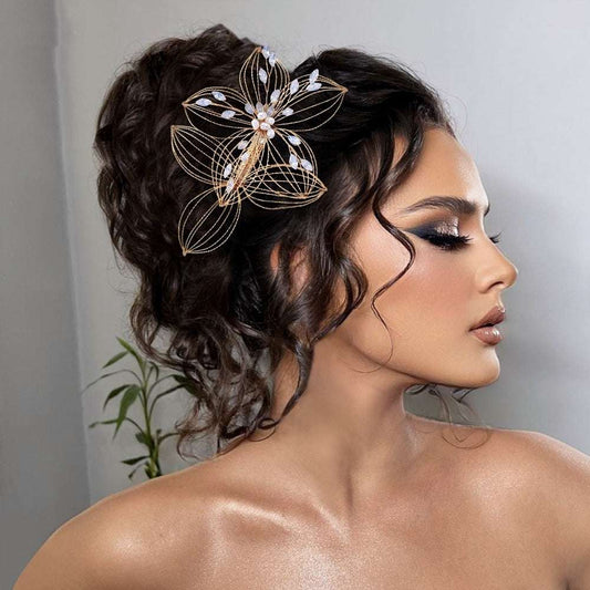 Elegant leaf design hair comb with gold wire and pearl accents worn in curly bridal updo