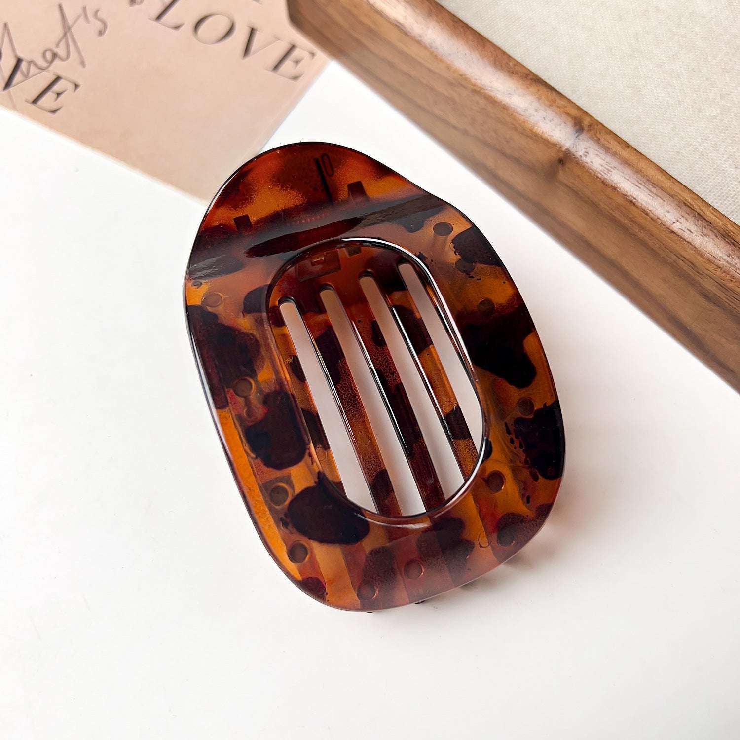 Tortoiseshell flat oval hair barrette with a glossy finish placed on white surface