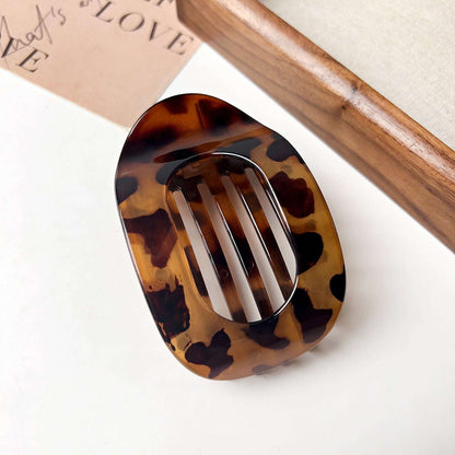 Tortoiseshell flat oval hair barrette for back head updo hairstyle on white surface
