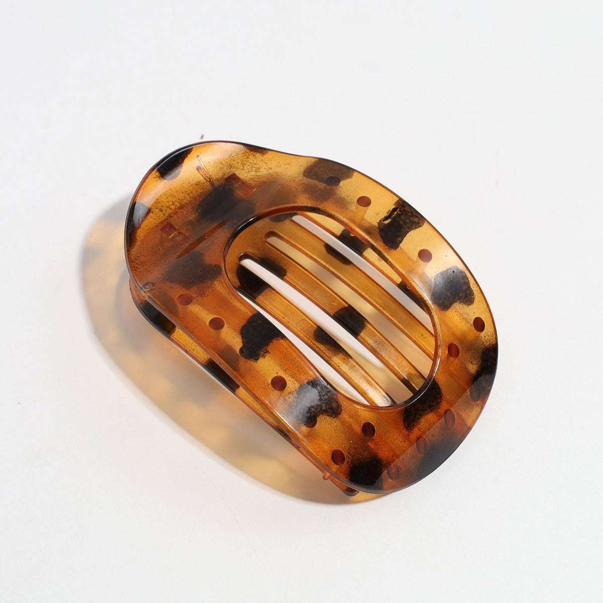 Tortoiseshell flat oval hair barrette with black spots and curved design for back head updo hair