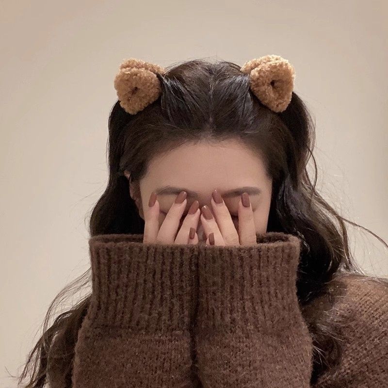 Fuzzy bear hair clips in brown adorning a woman's hair, complementing her cozy outfit
