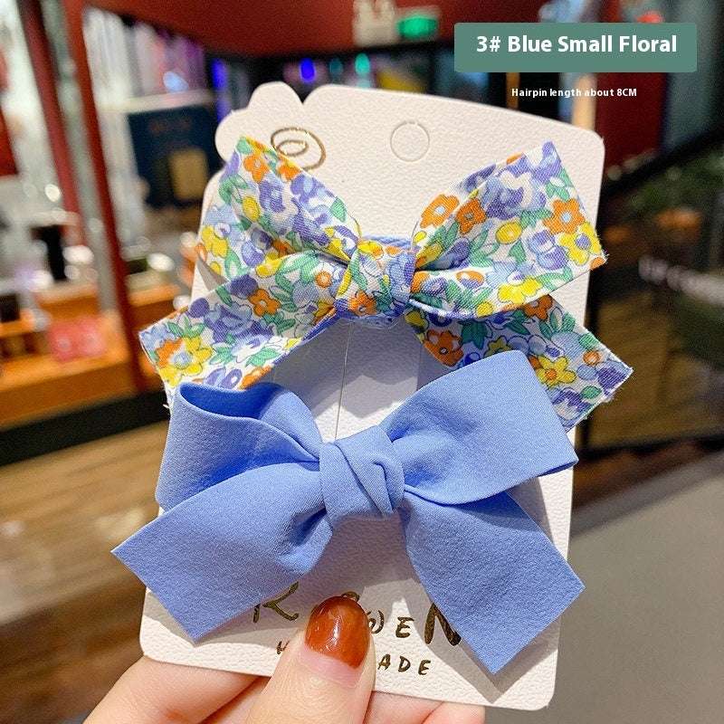 Luxury children's hairclips featuring floral and blue bow designs on a display card