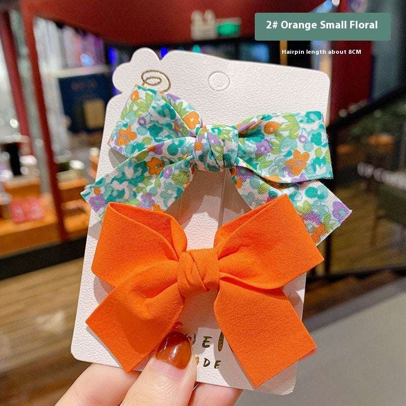 Luxury children's hairclips featuring floral and orange bows on a display card