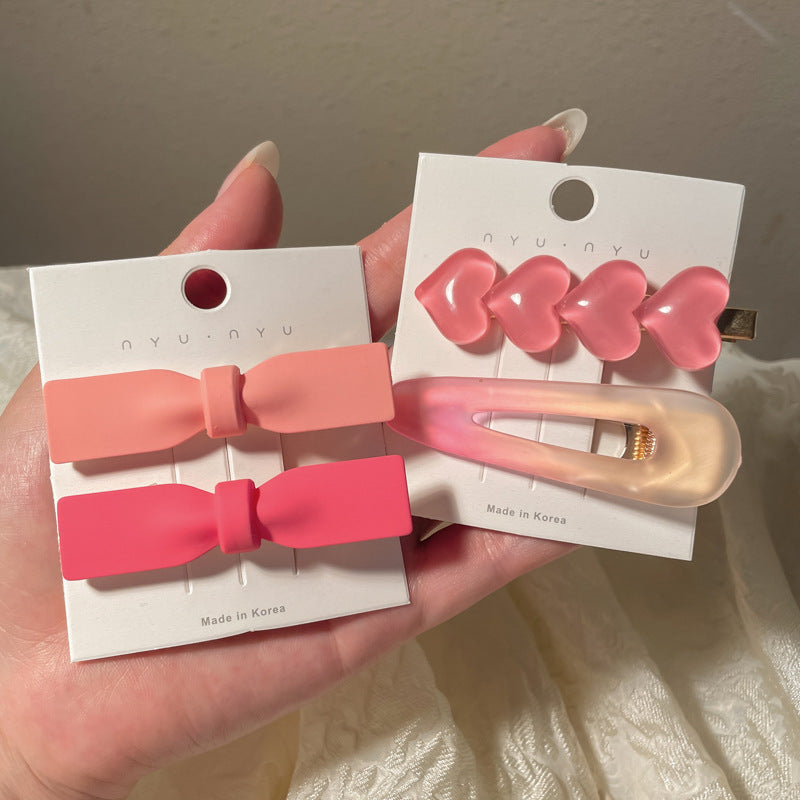 Set of pink hair accessories including heart-shaped hairclip and bow clips for stylish hairstyles