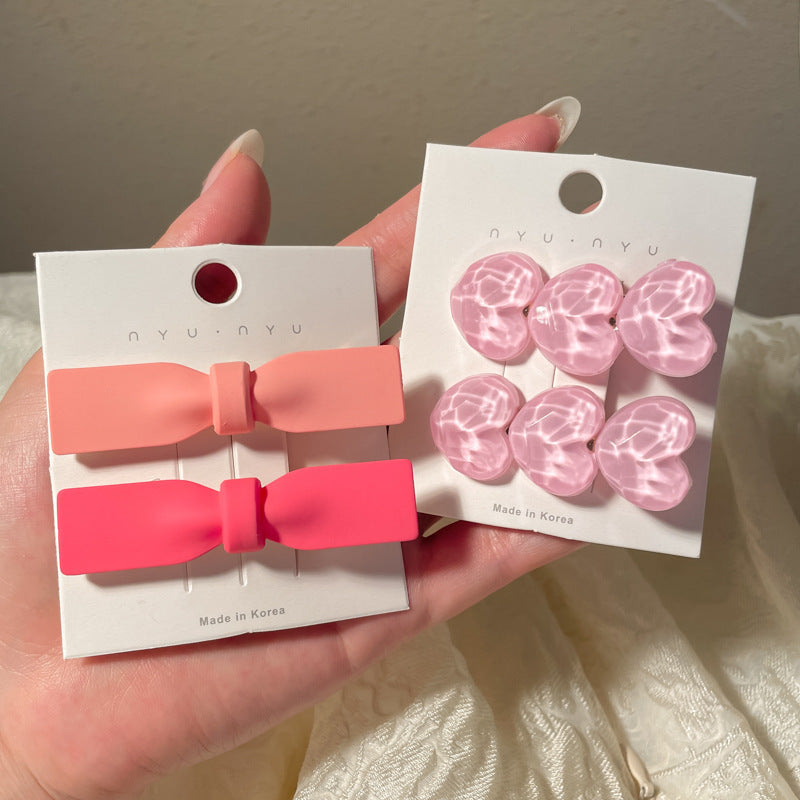 Set of heart-shaped hairclips in pink and coral with a glossy finish for stylish hairstyles