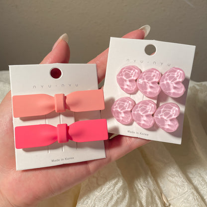 Set of heart-shaped hairclips in pink and coral with a glossy finish for stylish hairstyles