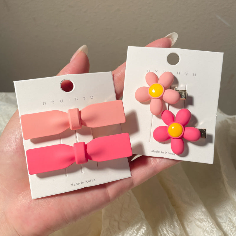Heart-shaped hairclip set featuring pink bows and colorful flower designs, perfect for stylish hair accessories