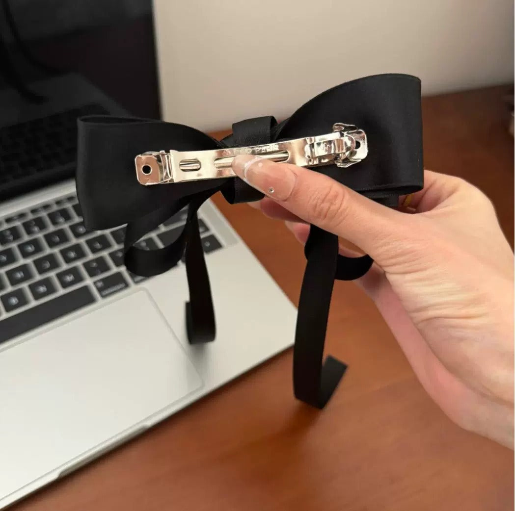 Hand holding a black bow hairpiece showcasing premium French barrettes for women with shiny finish