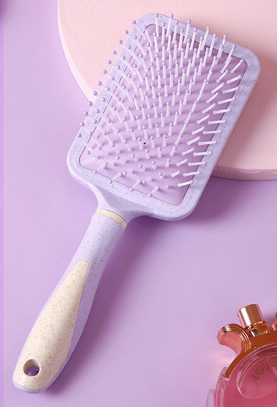 Purple professional airbag comb with beige handle and flexible bristles on pink background
