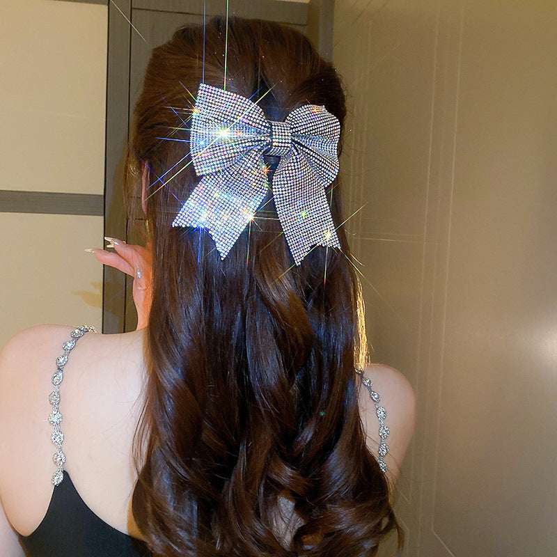 Sparkling hair clip in a bow shape, adorning long wavy hair for an elegant look
