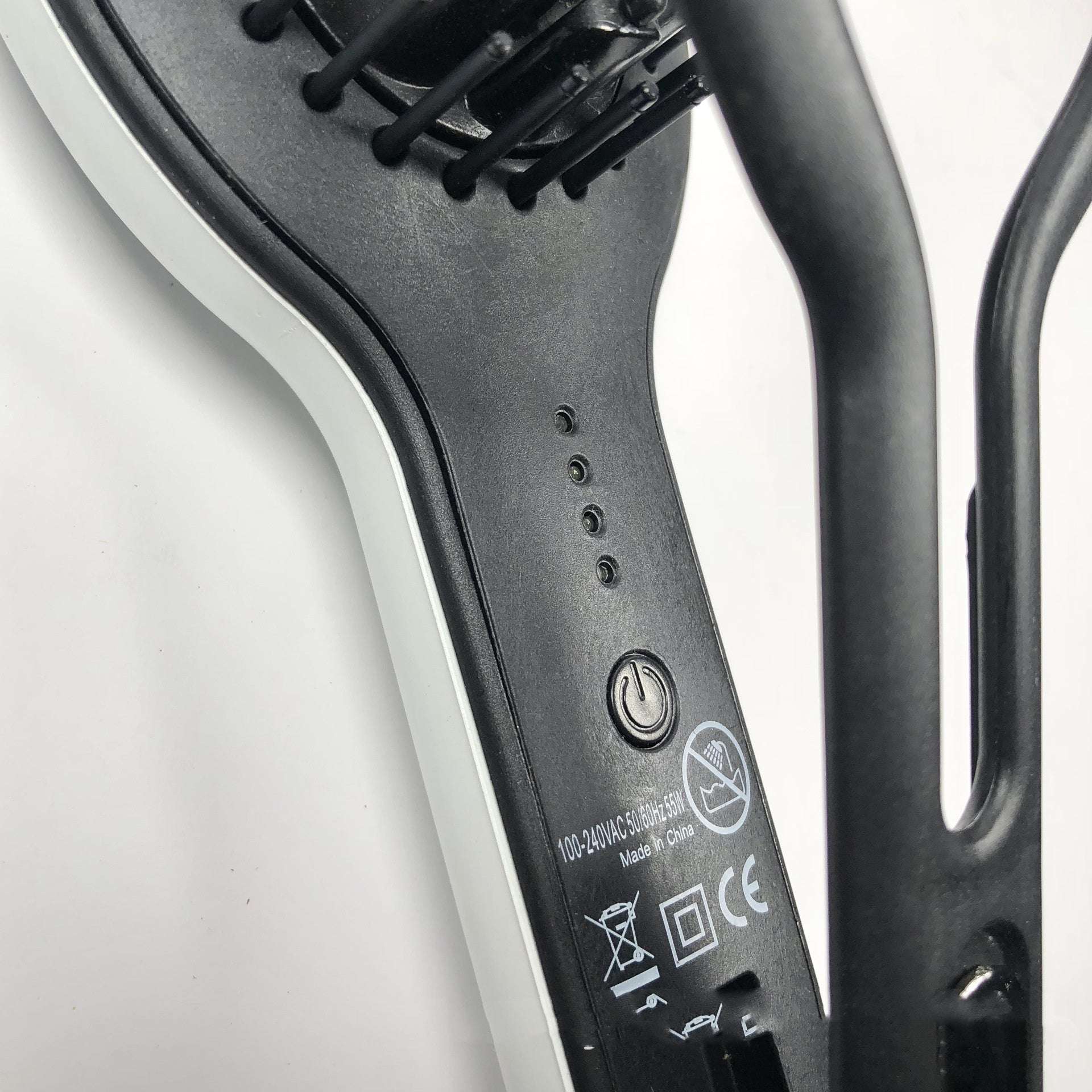 Close-up of black and white professional straight hair brush electric hair straightener with power button and indicator lights
