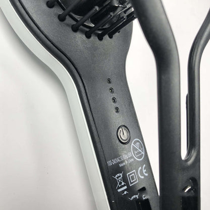 Close-up of black and white professional straight hair brush electric hair straightener with power button and indicator lights